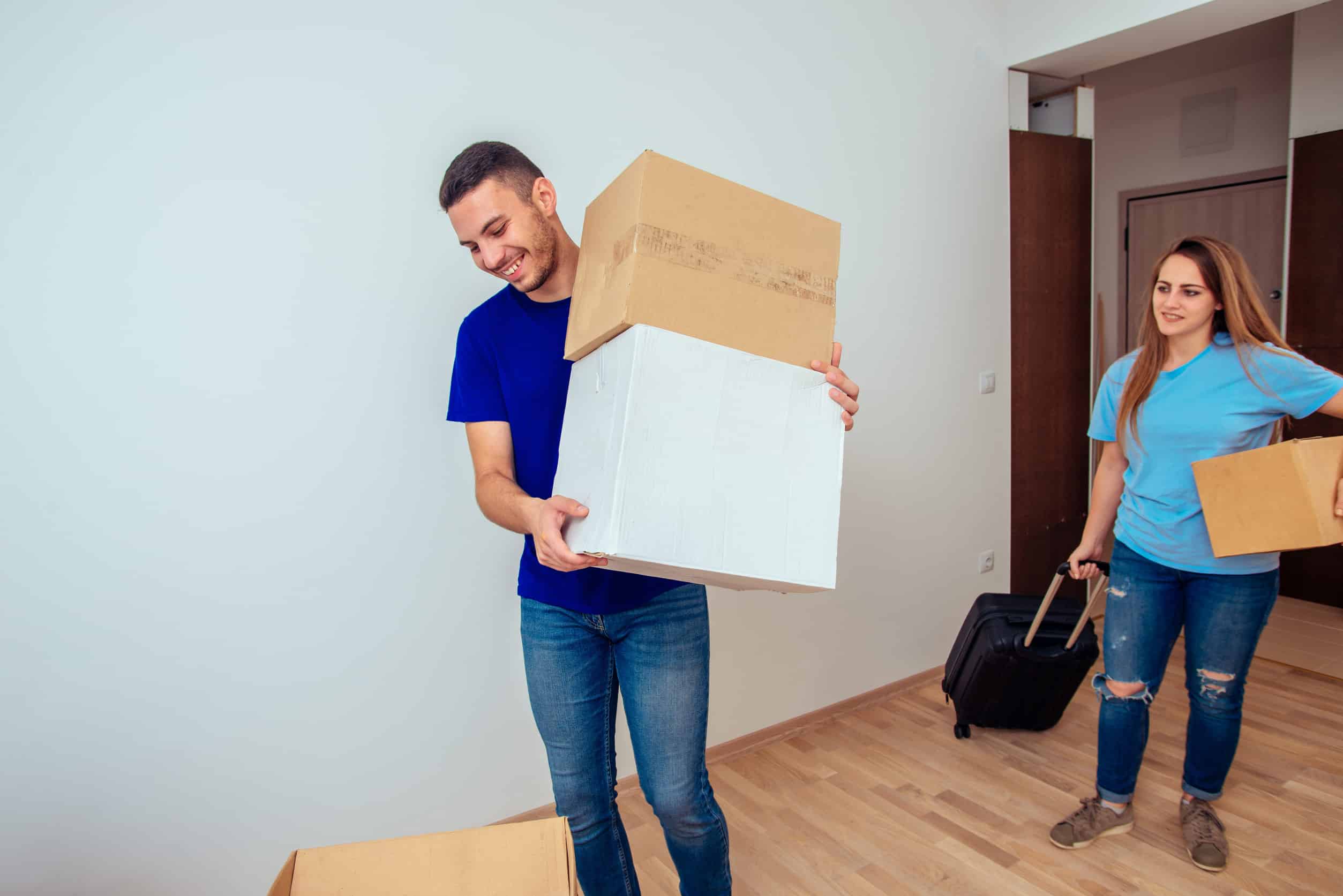 Cheerful couple moves into the new home while holding carboard boxes
